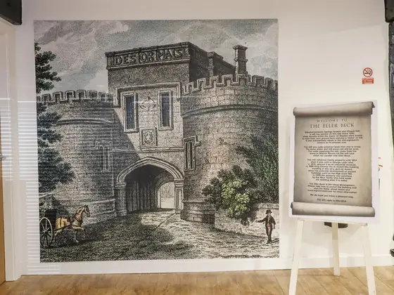 A wall-sized engraving of Skipton Castle gatehouse beside a printed panel about the Eller Beck