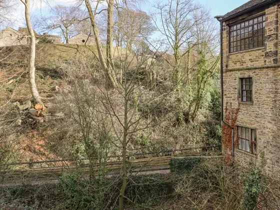 The mill from the wooded path, with the castle wall on the slope above
