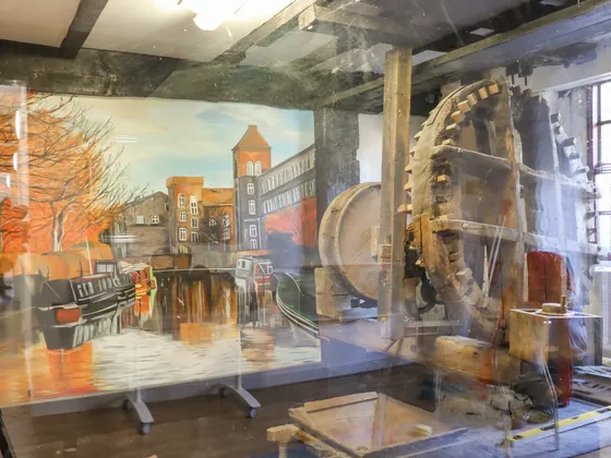 The mill&rsquo;s waterwheel and a painted canal scene behind the display glass